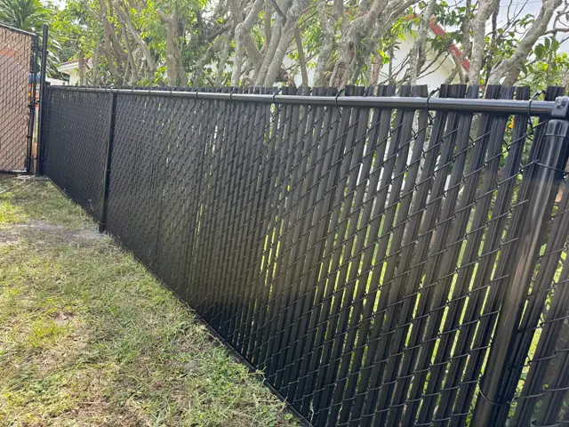 Black chain-link with privacy slats fence installed by Florida Fence Solution in Broward County